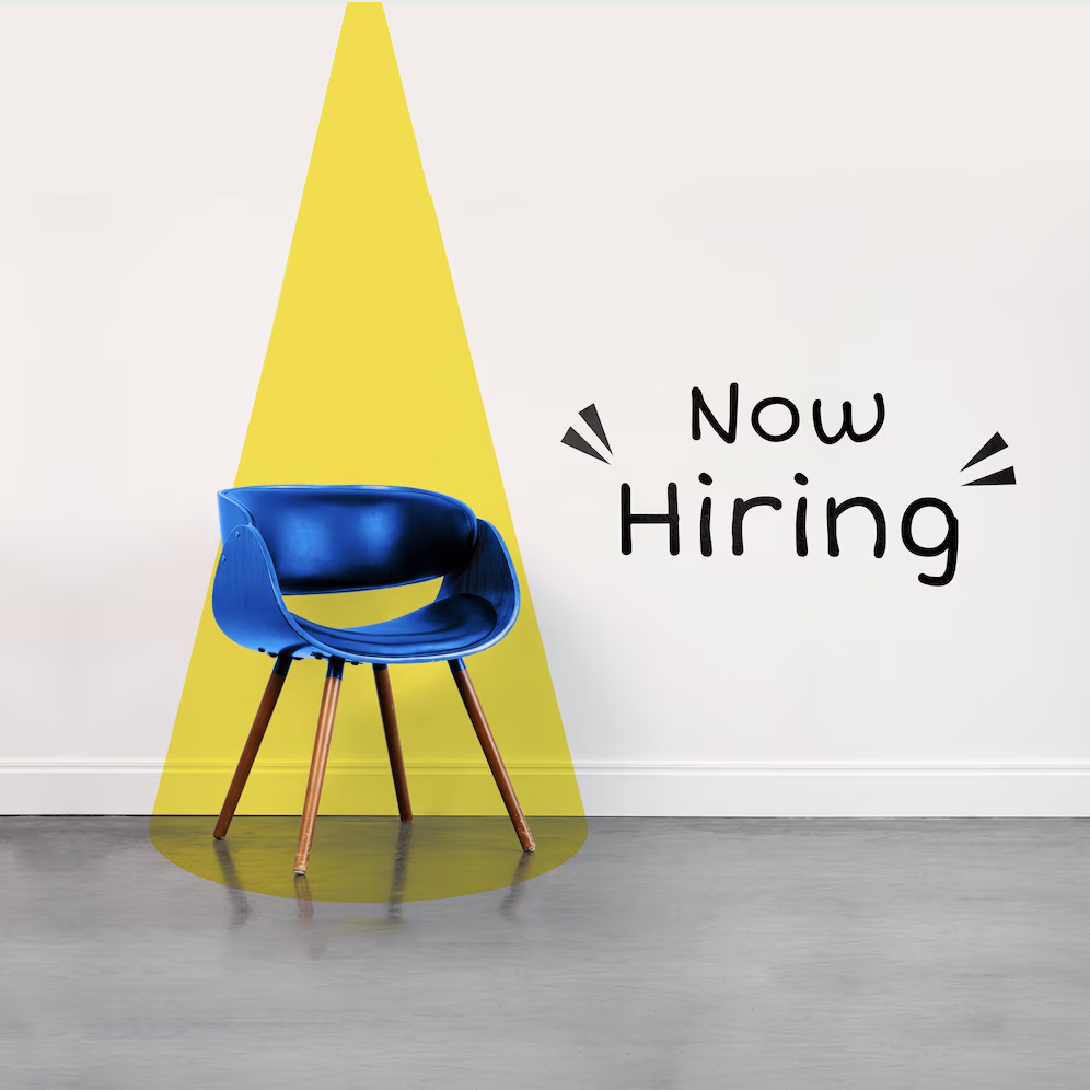 An empty blue chair, highlighted by light and the text "Now hiring"